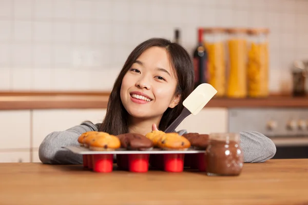 Mulher asiática na cozinha com bandeja cheia de muffins — Fotografia de Stock