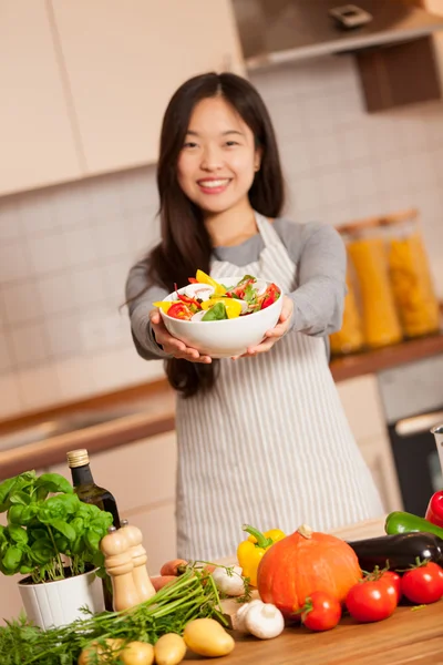 Asiática sorrindo mulher é segurando uma salada colorida em suas mãos — Fotografia de Stock