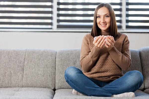 Mujer casual está sentado en el sofá con una taza de café —  Fotos de Stock