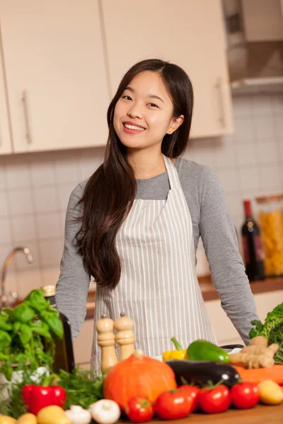 亚洲微笑的女人站在厨房里，丰富多彩的粒度 — 图库照片