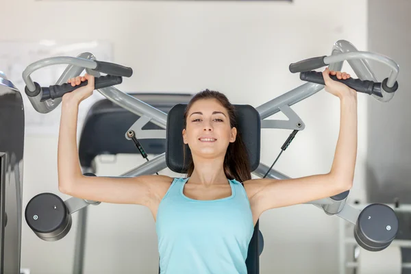 Jovem morena sorridente está treinando sua parte superior do corpo — Fotografia de Stock