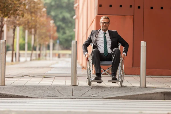 Empresário em cadeira de rodas atravessando a estrada — Fotografia de Stock