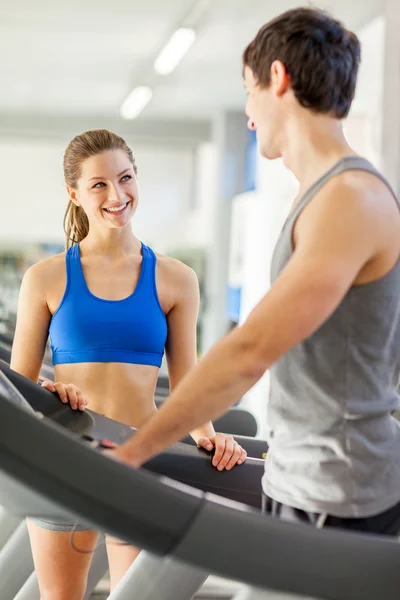 Female fitness instructor smiling towards young man on a treadmi — Stock Photo, Image