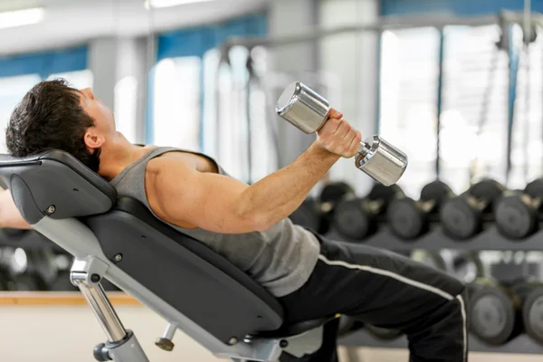 Young man is working out his arms with dumbbells — Stock Photo, Image