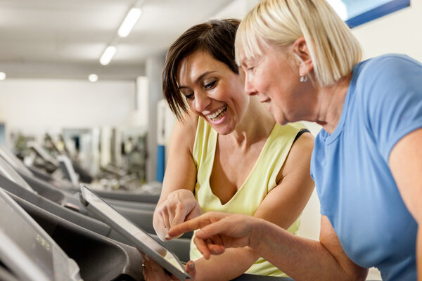 Female fitness trainer is discussing program with woman on a tre