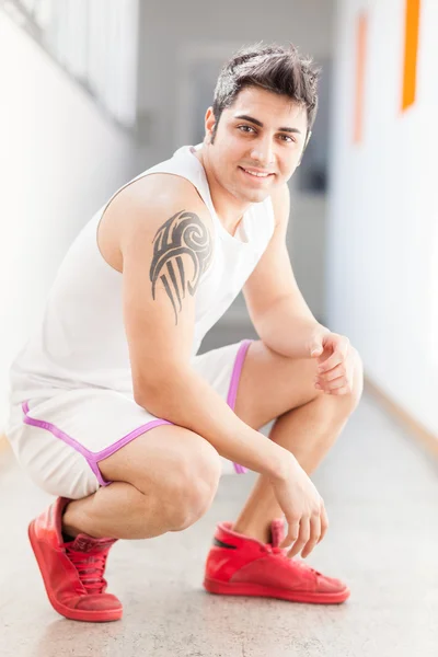 Hombre sonriente en ropa deportiva en un pasillo —  Fotos de Stock