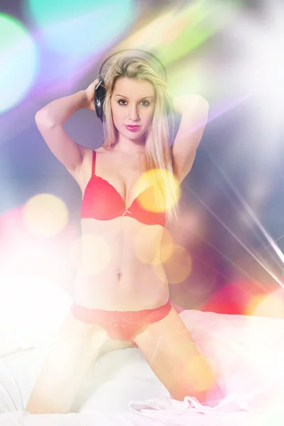 Blonde vrouw met rode lingerie en hoofdtelefoons — Stockfoto
