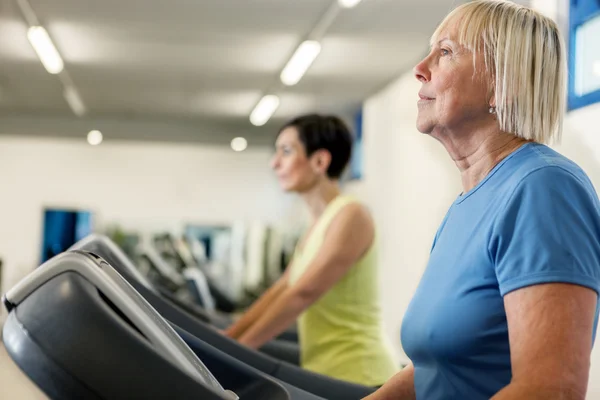 Two mature women are running on a treadmill — Stock Photo, Image