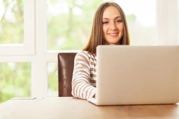 Sorrindo morena mulher está trabalhando com notebook em casa — Fotografia de Stock