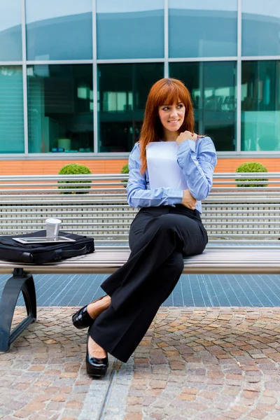 Businesswoman sitting outside on a metal bench — Stock Photo, Image