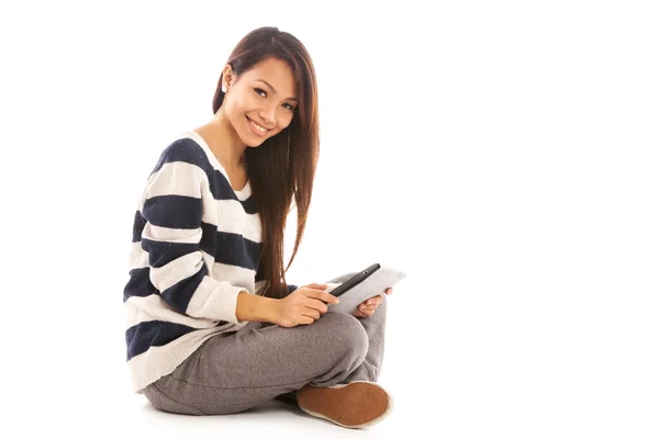 Smiling asian girl with tablet pc is sitting on the floor over w — Stock Photo, Image