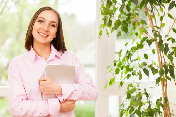 Mulher sorrindo de pé com um tablet pc — Fotografia de Stock