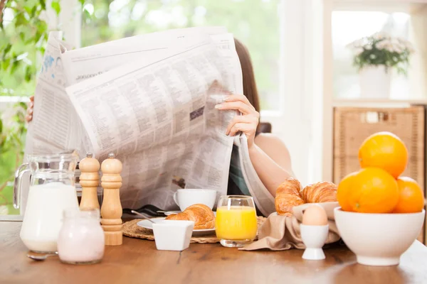 Vrouw is een krant lezen terwijl het hebben van ontbijt — Stockfoto