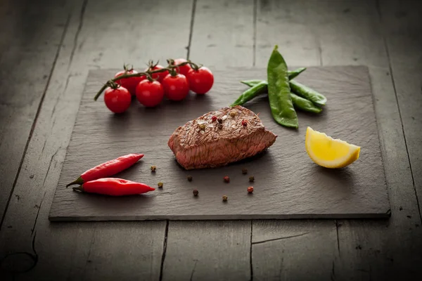 Sebzelerin üzerine taş plaka ile lezzetli biftek — Stok fotoğraf