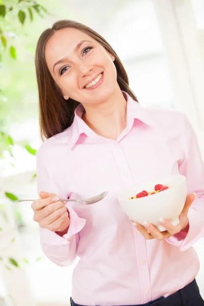 웃는 여자는 아침 식사에 대 한 열매와 콘플레이크를 데 — 스톡 사진
