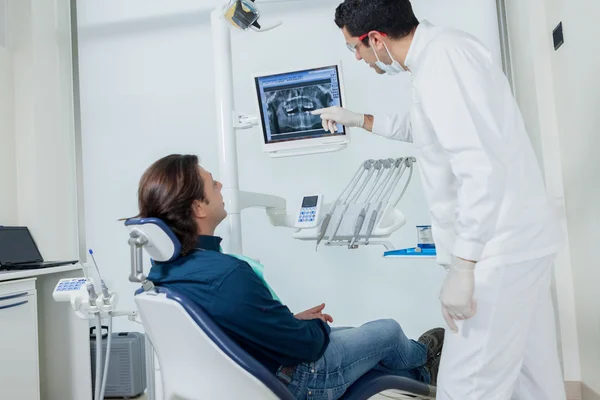 El dentista está mostrando a su paciente en el monitor —  Fotos de Stock