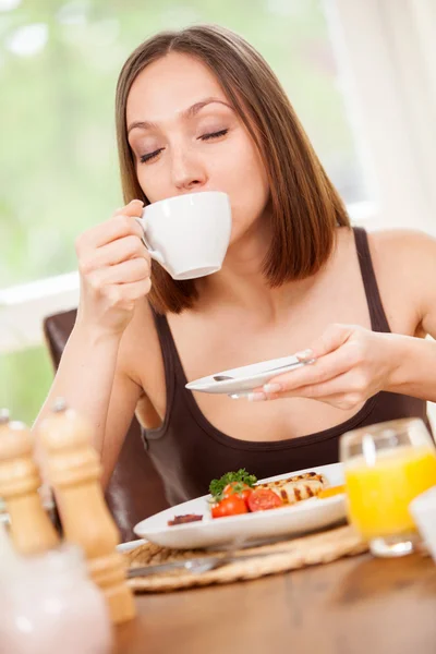 Young woman is drinking a hot cup of coffee — Stock Photo, Image