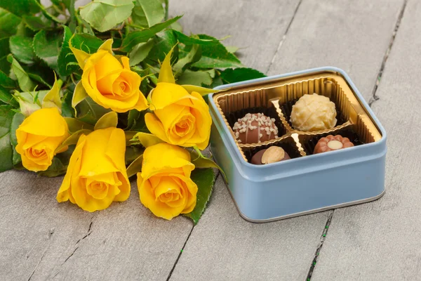 Chokladpraliner och gula rosor — Stockfoto