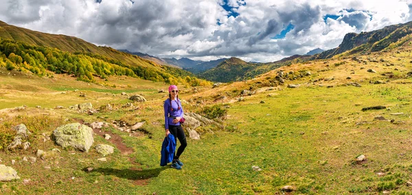 Mujer con gafas de sol contempla las montañas del Cáucaso en otoño. El turista está situado en el prado alpino . — Foto de Stock