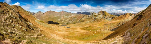 La pintoresca vista superior sobre el valle entre las montañas, colinas, laderas de montaña con hierba amarilla seca sobre un fondo de cielo azul con nubes en el otoño — Foto de Stock