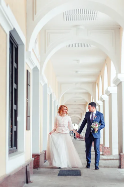 Mariée et marié marchant parmi les colonnes sur la place de la ville — Photo