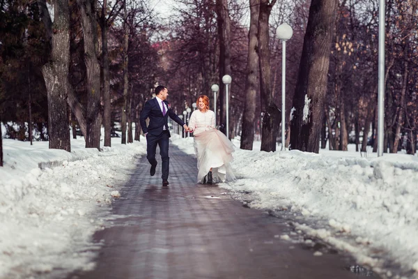 Menyasszony és a vőlegény. boldog esküvői pár havas tavaszi park — Stock Fotó