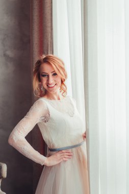 Güzel Gelin çiçek grup ile pencereden duran.