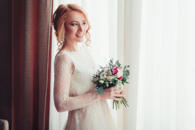 Güzel Gelin çiçek grup ile pencereden duran.