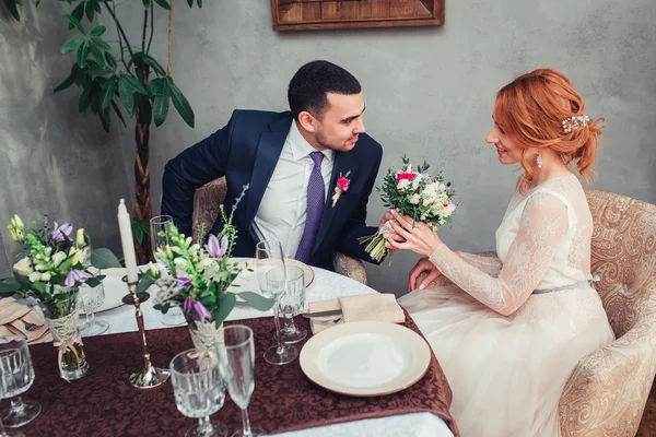 Bella sposa e sposo baciare al tavolo del ristorante rustico — Foto Stock