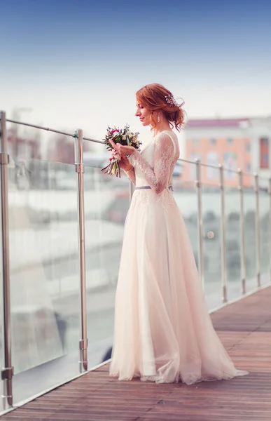 Emocional novia de pelo rojo en vestido blanco posando en el balcón con c — Foto de Stock