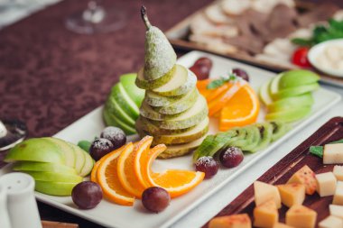 Yakın fotoğraf seçici odak beyaz tabak, üzüm, elma, armut, portakal, üzerinde farklı taze meyve ile kivi dilimleri ve şeker tepesi tarafından kapalı