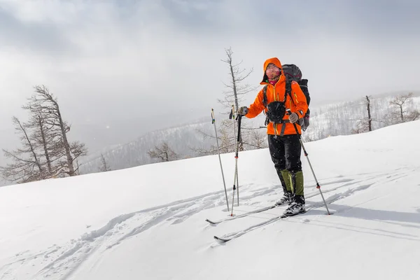 Lyžař nošení batohu a sestupné příkrém hřebenu v zimě — Stock fotografie