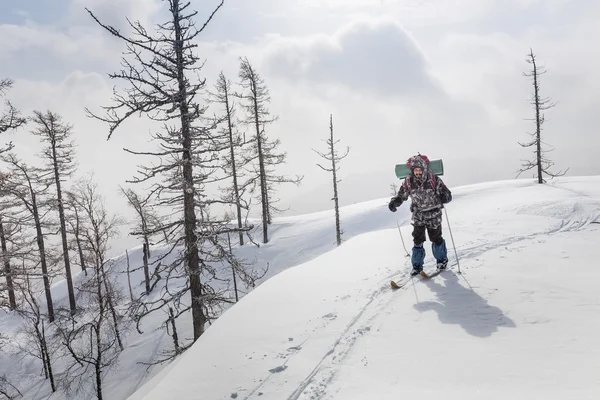 Caminhadas de esquiador masculino com uma mochila em montanhas de inverno e floresta — Fotografia de Stock