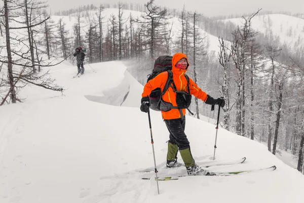 Viajero ascendiendo una montaña cubierta de nieve en esquís de travesía en ov — Foto de Stock