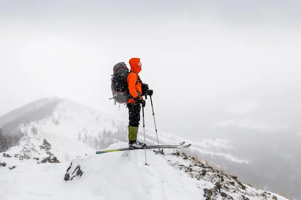 Mann mit Skiern und Rucksack steht auf einem Berggipfel — Stockfoto