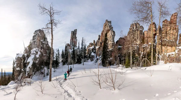 Winter landscape with rocks in the forest and a group of tourist