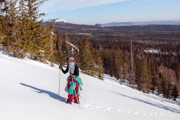 Жіночий альпіністка, одягнена в червоний колір, піднімається на сніговий схил мо — стокове фото