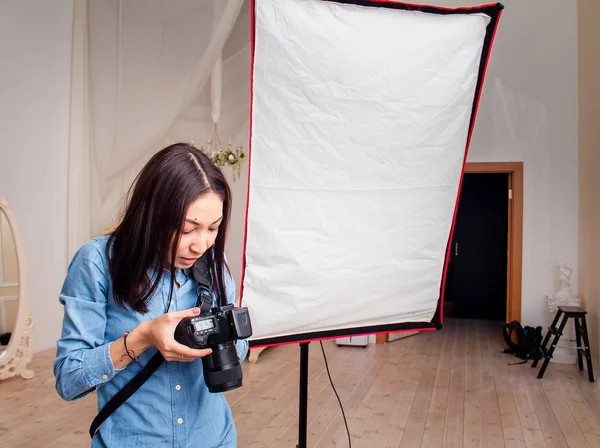 Fotógrafa mujer ajusta el equipo flash, cámara y softbox en el estudio de fotografía interior —  Fotos de Stock