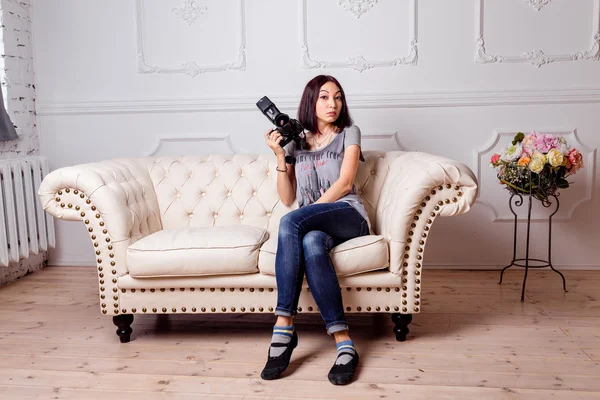 Portrait of smiling young woman with dslr photo camera sitting in loft apartment — Stock Photo, Image