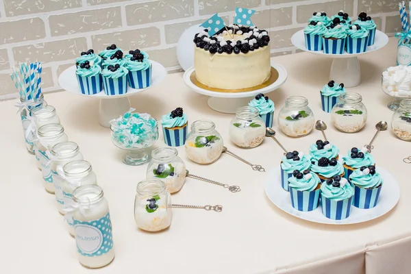 Dulce bebé caramelo buffet en estilo azul con un montón de pasteles decorados y dulces — Foto de Stock