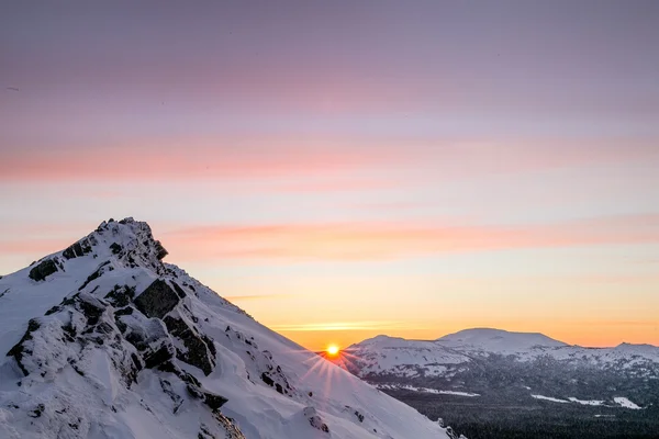 Sunset in winter mountains covered by snow. Shining sun on the b