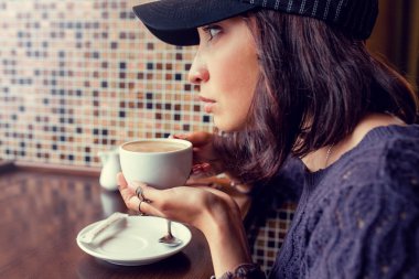 Kız yol kenarı kafede kahve içiyor. Tonda sıcak renkler