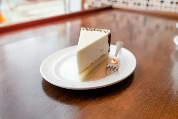 Scheibe Käsekuchen auf weißem Holztisch im Café — Stockfoto