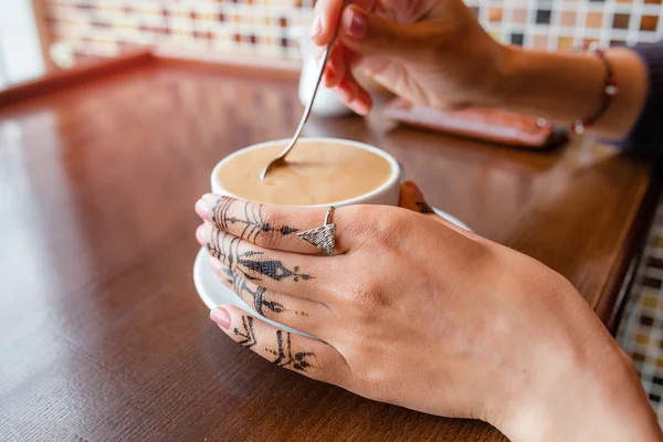 Рука с Мехенди держа кофе в кафе — стоковое фото