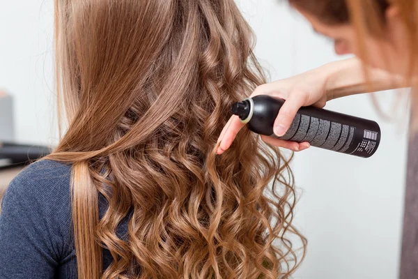 Beleza, penteado e conceito de pessoas - close-up de cabeça de mulher e mãos estilistas com spray de cabelo fazendo penteado no salão barbeiro — Fotografia de Stock