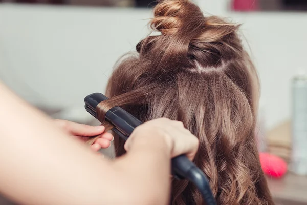 Closeup of hairdresser doing hairstyle with hair iron — Stock Photo, Image