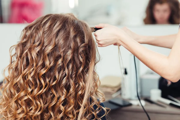 Coiffeur bouclage cheveux femme avec fer électrique boucleur pince. Coiffeur faire coiffure fille . — Photo