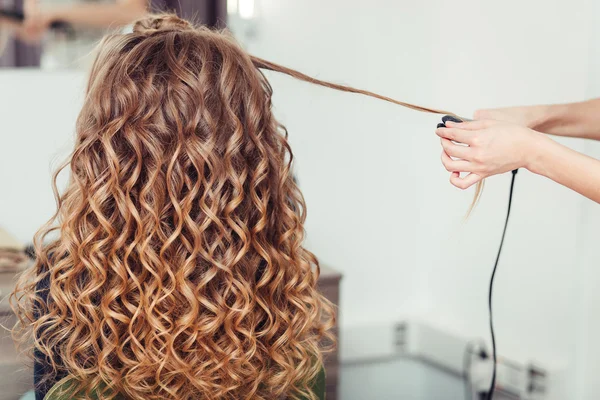 Kapper curling vrouw haar met strijkijzer krultang tong. Haarstylist maken meisje kapsel. — Stockfoto