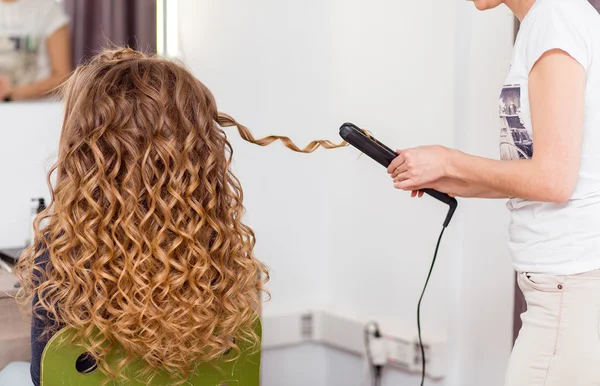 Kuaför elektrik demir kıvırıcı tong kadın saç kıvırma. Kuaförlük yapıyor kız saç modeli. — Stok fotoğraf