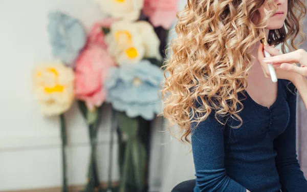 Long female blond curly hair during hair dressing with curler, close-up, on barber interior background — Stock Photo, Image